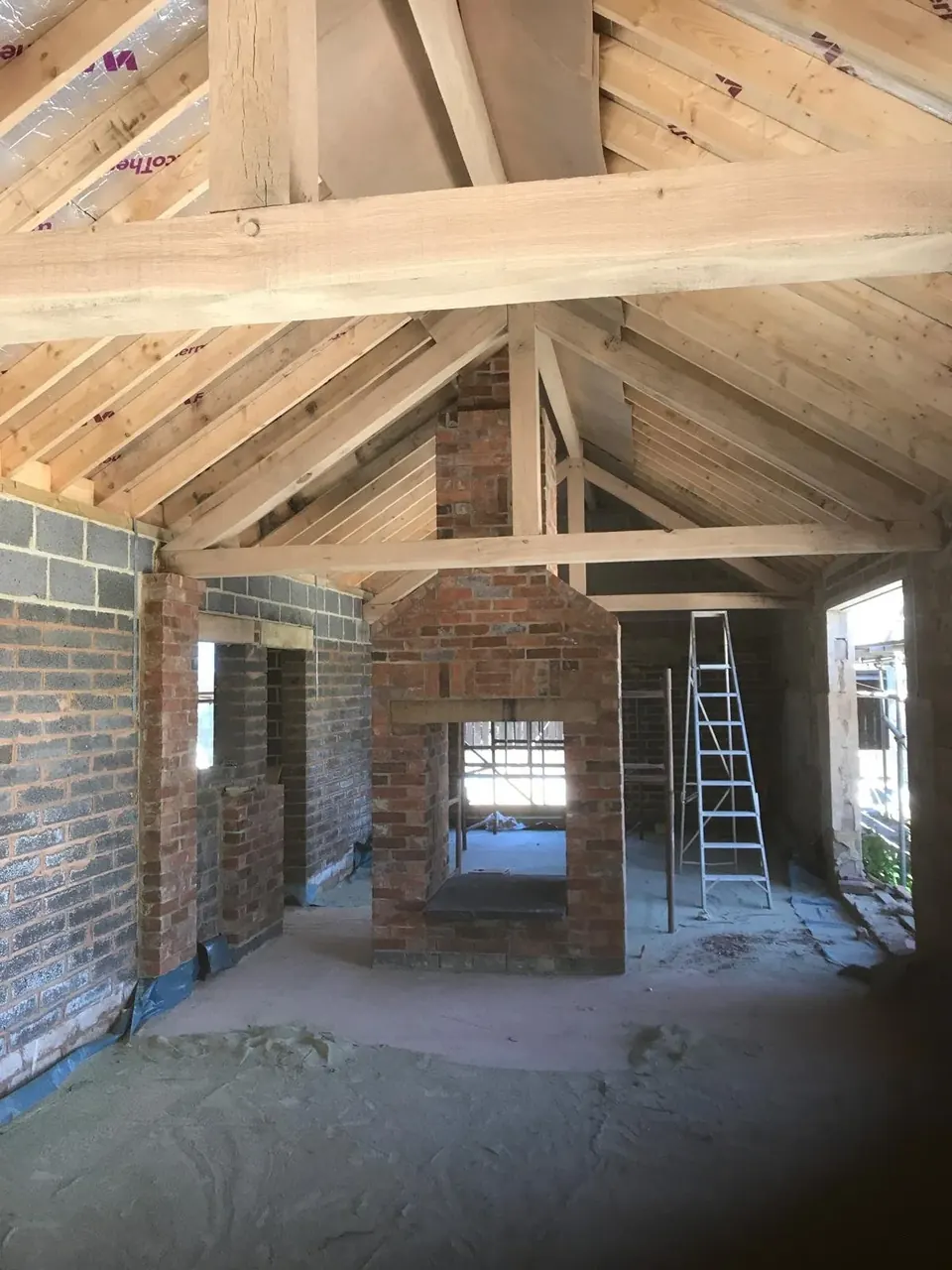 Barn conversion interior with oak roof trusses and brick walls blast cleaned back to the original timber and brick