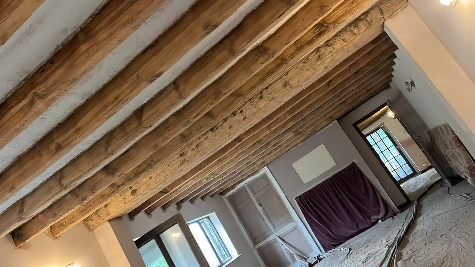 Beamed ceiling in a cottage after the old dark finish was blasted off the timber
