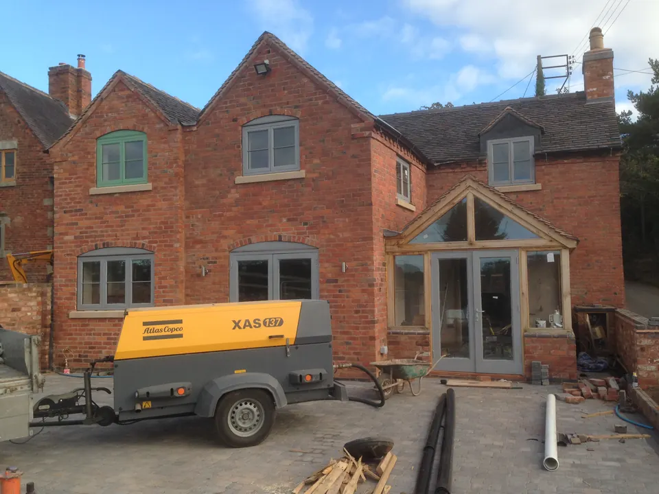 Brick house with a mobile compressor outside, after the brickwork was shot blasted