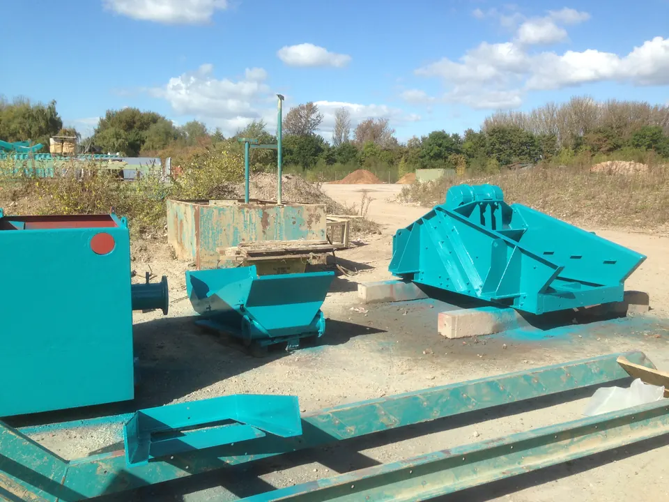 Crusher bodies blasted and painted turquoise on site at a quarry