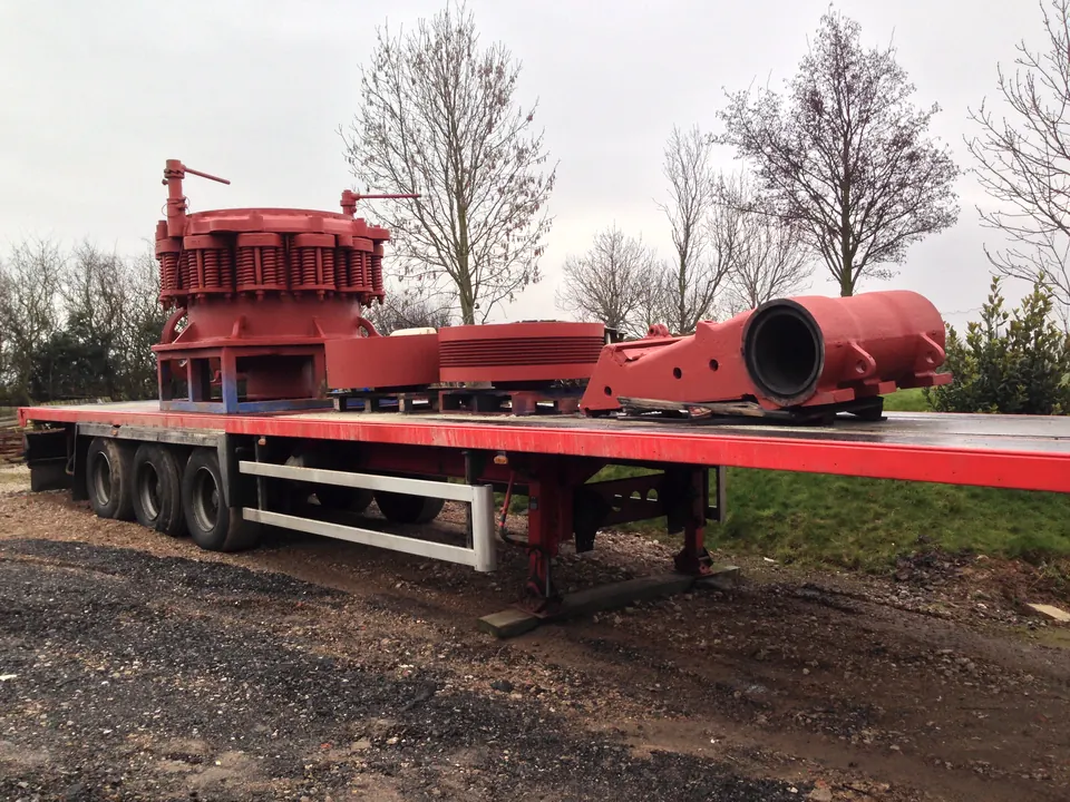 Crusher parts blasted and primed in red oxide, loaded on a flatbed trailer