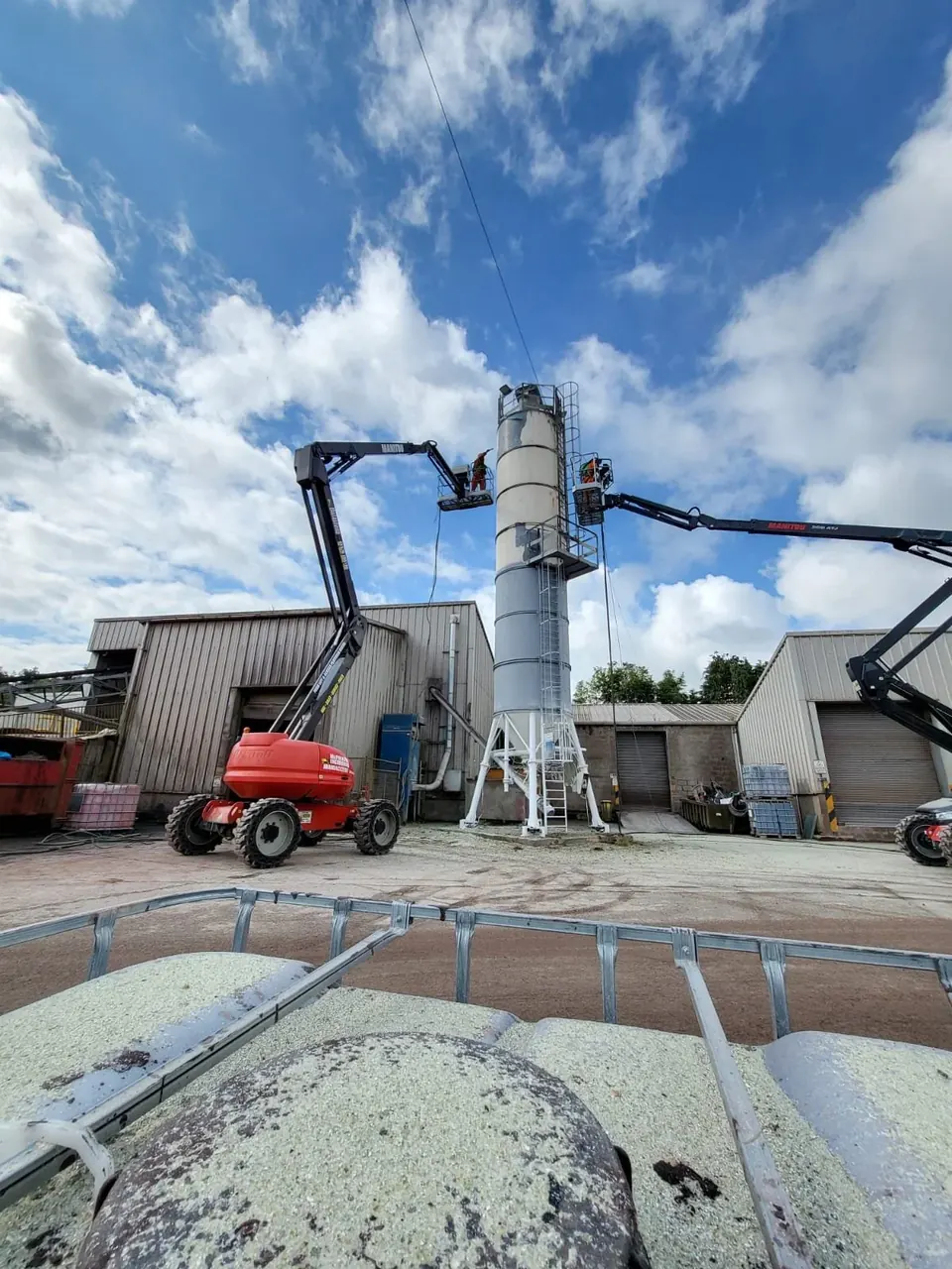 Two cherry pickers lifting Belmont operatives alongside a steel silo being blasted at the yard near Burton upon Trent